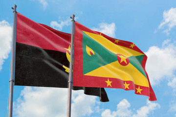 Grenada and Angola flags waving in the wind against white cloudy blue sky together. Diplomacy concept, international relations.