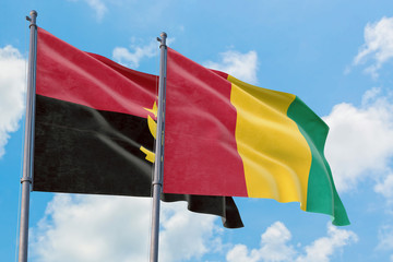 Guinea and Angola flags waving in the wind against white cloudy blue sky together. Diplomacy concept, international relations.