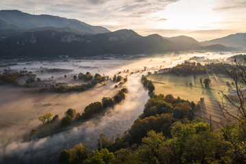 Abstract with Airuno on Adda river in Italy at sunrise with myst fog trees foliage in autumn fall season
