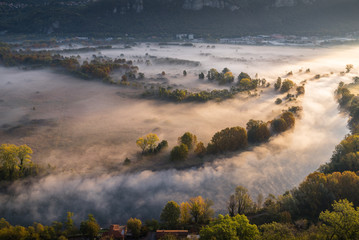 Abstract with Airuno on Adda river in Italy at sunrise with myst fog trees foliage in autumn fall season