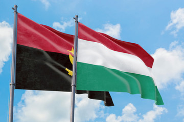 Hungary and Angola flags waving in the wind against white cloudy blue sky together. Diplomacy concept, international relations.