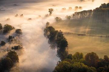 Abstract with Airuno on Adda river in Italy at sunrise with myst fog trees foliage in autumn fall season