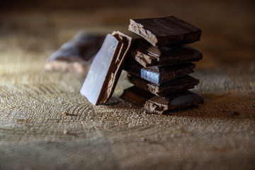 Chocolate pyramid from the pieces of chocolate with filling on a wooden table.