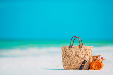 Beach accessories - bag, straw hat, sunglasses on white beach