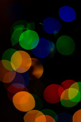 Closeup of colored Christmas bokeh on black background.