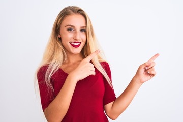 Young beautiful woman wearing red t-shirt standing over isolated white background smiling and looking at the camera pointing with two hands and fingers to the side.