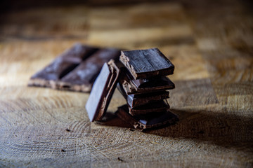 Black chocolate with truffle filling on a kitchen wooden board.