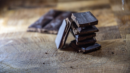 Black chocolate with truffle filling on a kitchen wooden board.