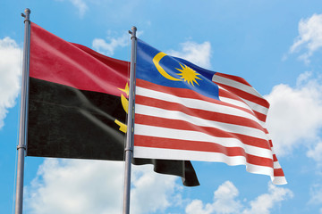 Malaysia and Angola flags waving in the wind against white cloudy blue sky together. Diplomacy concept, international relations.