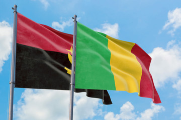 Mali and Angola flags waving in the wind against white cloudy blue sky together. Diplomacy concept, international relations.