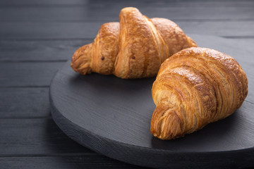 Croissants on a black wooden table. Croissant breakfast. Croissants on a wooden board and a black wooden table. Fresh French Baked Croissants. Warm Fresh Buttery Rolls. Free space for text.