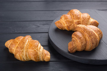 Croissants on a black wooden table. Croissant breakfast. Croissants on a wooden board and a black wooden table. Fresh French Baked Croissants. Warm Fresh Buttery Rolls. Free space for text.