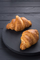 Croissants on a black wooden table. Croissant breakfast. Croissants on a wooden board and a black wooden table. Fresh French Baked Croissants. Warm Fresh Buttery Rolls. Free space for text.