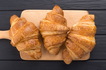 Croissants on a black wooden table. Croissant breakfast. Croissants on a wooden board and a black wooden table. Fresh French Baked Croissants. Warm Fresh Buttery Rolls. Free space for text. View from 