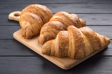 Croissants on a black wooden table. Croissant breakfast. Croissants on a wooden board and a black wooden table. Fresh French Baked Croissants. Warm Fresh Buttery Rolls. Free space for text.