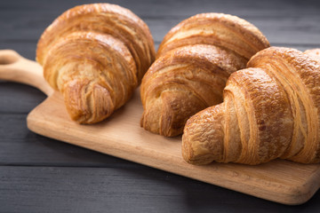 Croissants on a black wooden table. Croissant breakfast. Croissants on a wooden board and a black wooden table. Fresh French Baked Croissants. Warm Fresh Buttery Rolls. Free space for text.