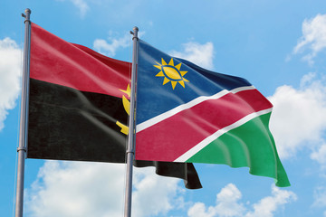 Namibia and Angola flags waving in the wind against white cloudy blue sky together. Diplomacy concept, international relations.