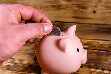 Man putting cent coin in a pink piggy bank