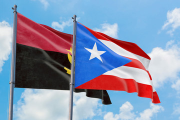 Puerto Rico and Angola flags waving in the wind against white cloudy blue sky together. Diplomacy concept, international relations.