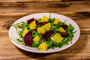 Salad with arugula, orange and beetroot in a ceramic plate