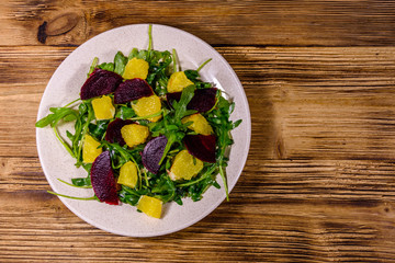 Salad with arugula, orange and beetroot in a ceramic plate. Top view