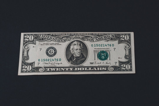 One twenty dollar bill isolated on a black background.