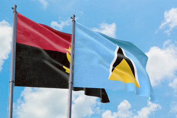 Saint Lucia and Angola flags waving in the wind against white cloudy blue sky together. Diplomacy concept, international relations.