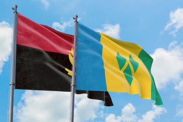 Saint Vincent And The Grenadines and Angola flags waving in the wind against white cloudy blue sky together. Diplomacy concept, international relations.