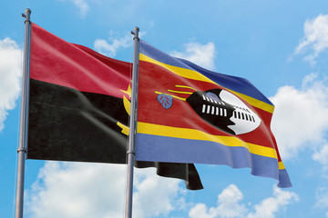 Swaziland and Angola flags waving in the wind against white cloudy blue sky together. Diplomacy concept, international relations.