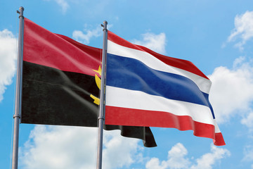 Fototapeta premium Thailand and Angola flags waving in the wind against white cloudy blue sky together. Diplomacy concept, international relations.