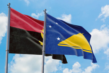 Tokelau and Angola flags waving in the wind against white cloudy blue sky together. Diplomacy concept, international relations.