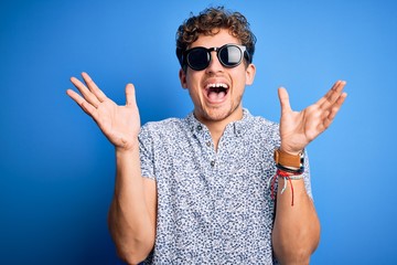 Young blond handsome man with curly hair on vacation wearing striped polo and sunglasses...