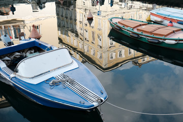 Boats moored on waterway and antique building reflected on water
