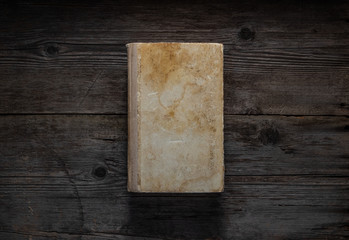 Closed book on vintage wooden background.  Old book on the wooden table. Closed book with empty cover laying on wooden table.