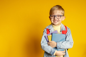 funny kid schoolboy boy with books on yellow background