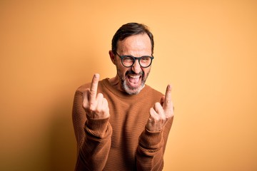 Middle age hoary man wearing brown sweater and glasses over isolated yellow background Showing...