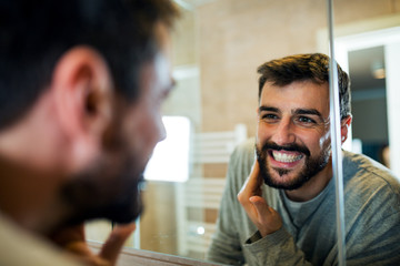 Handsome beard man applying hydrating cream on face