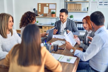 Obraz premium Group of business workers working together. Sitting on desk using laptop reading documents at the office