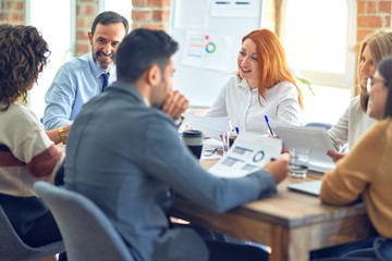 Group of business workers working together. Sitting on desk using laptop reading documents at the office