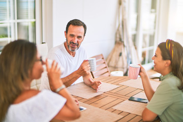 Fototapeta premium Beautiful family sitting on terrace drinking cup of coffee speaking and smiling