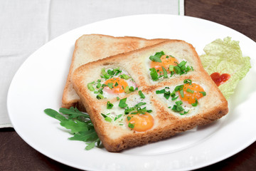Fried scrambled quail eggs and bread in the shape of 4 hearts (like lucky clover) with toasts and fresh vegetables served on a wooden table. Creative breakfast on Valentine's or Mother's Day, closeup