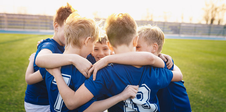 Happy kids in elementary school sports team celebrating soccer succes in tournament final game. Children soccer team team gathering together in a circle, to strategize, motivate and celebrate