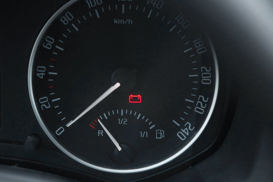 .Close up shot of a car dashboard with the battery icon lit.