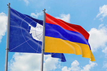 Armenia and Antarctica flags waving in the wind against white cloudy blue sky together. Diplomacy concept, international relations.