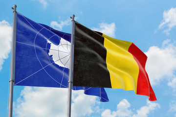 Belgium and Antarctica flags waving in the wind against white cloudy blue sky together. Diplomacy concept, international relations.