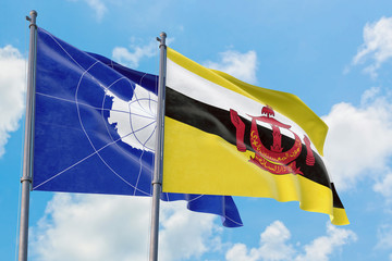 Brunei and Antarctica flags waving in the wind against white cloudy blue sky together. Diplomacy concept, international relations.