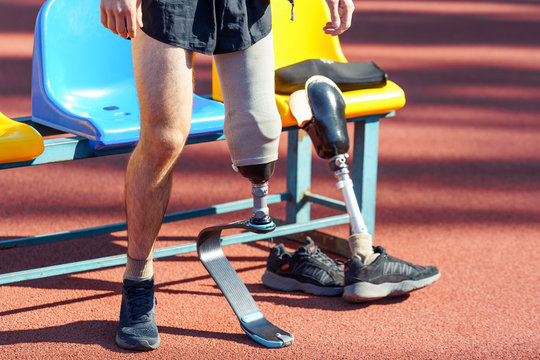Sportsman with prosthetic leg standing near seats and getting ready for a race
