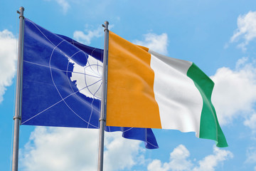 Cote D'Ivoire and Antarctica flags waving in the wind against white cloudy blue sky together. Diplomacy concept, international relations.