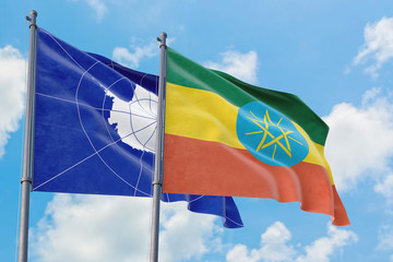 Ethiopia and Antarctica flags waving in the wind against white cloudy blue sky together. Diplomacy concept, international relations.
