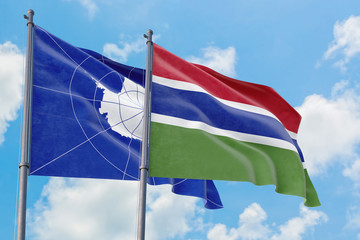Gambia and Antarctica flags waving in the wind against white cloudy blue sky together. Diplomacy concept, international relations.
